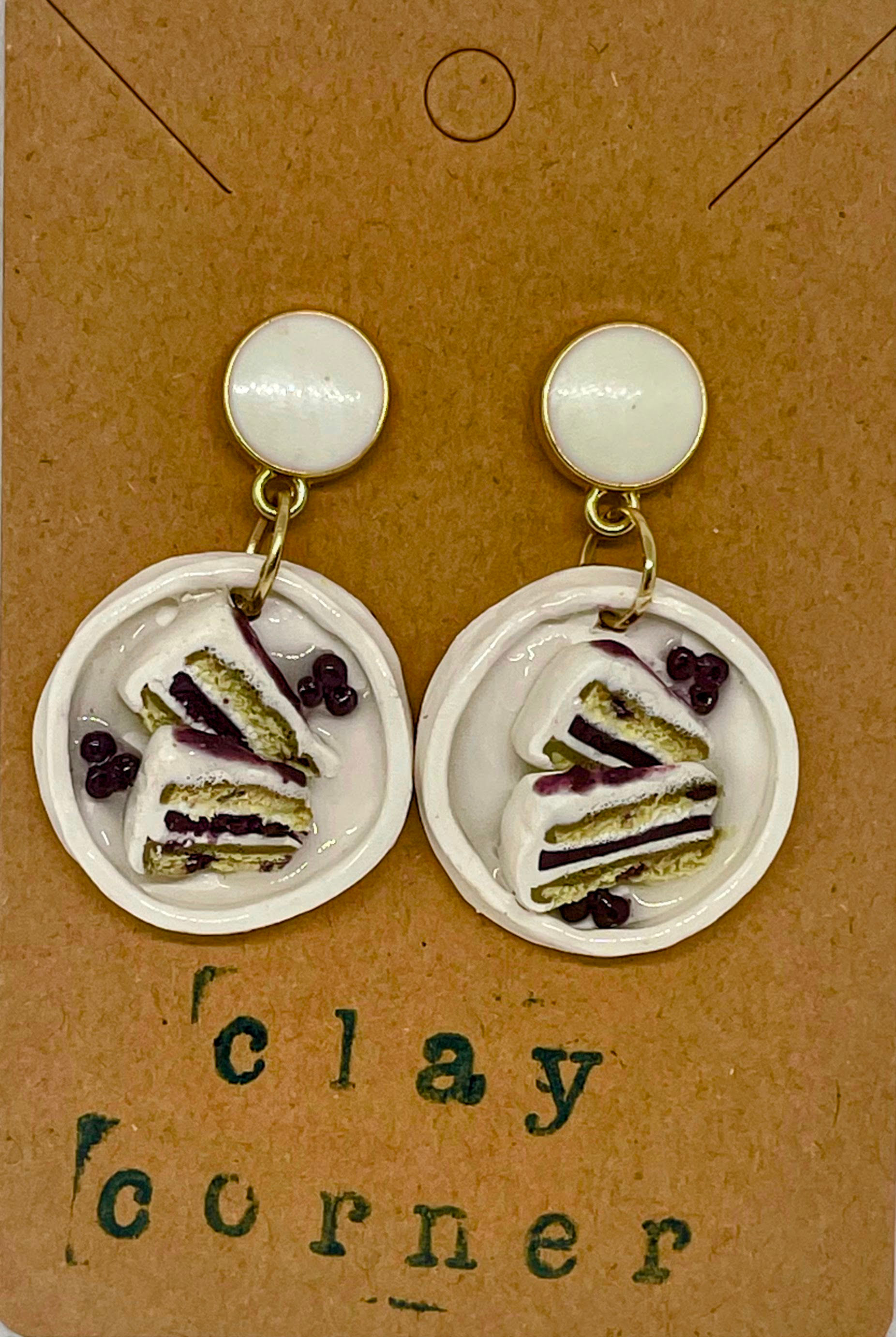 drop earrings of a white circular dessert tray with two blueberry cake slices and blueberries