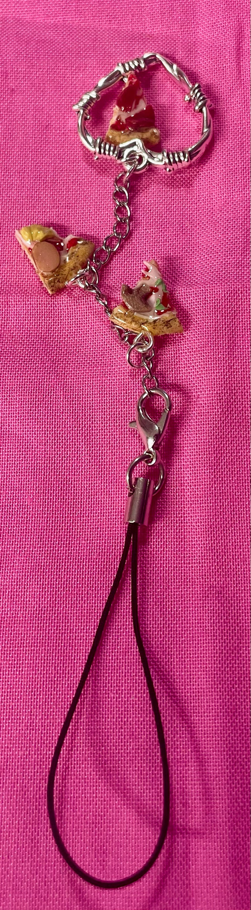 Thumbnail: phone charm of a slice of pepperoni pizza inside of a barbed wire heart with a hawaiian pizza slice and mushroom pepper slice
