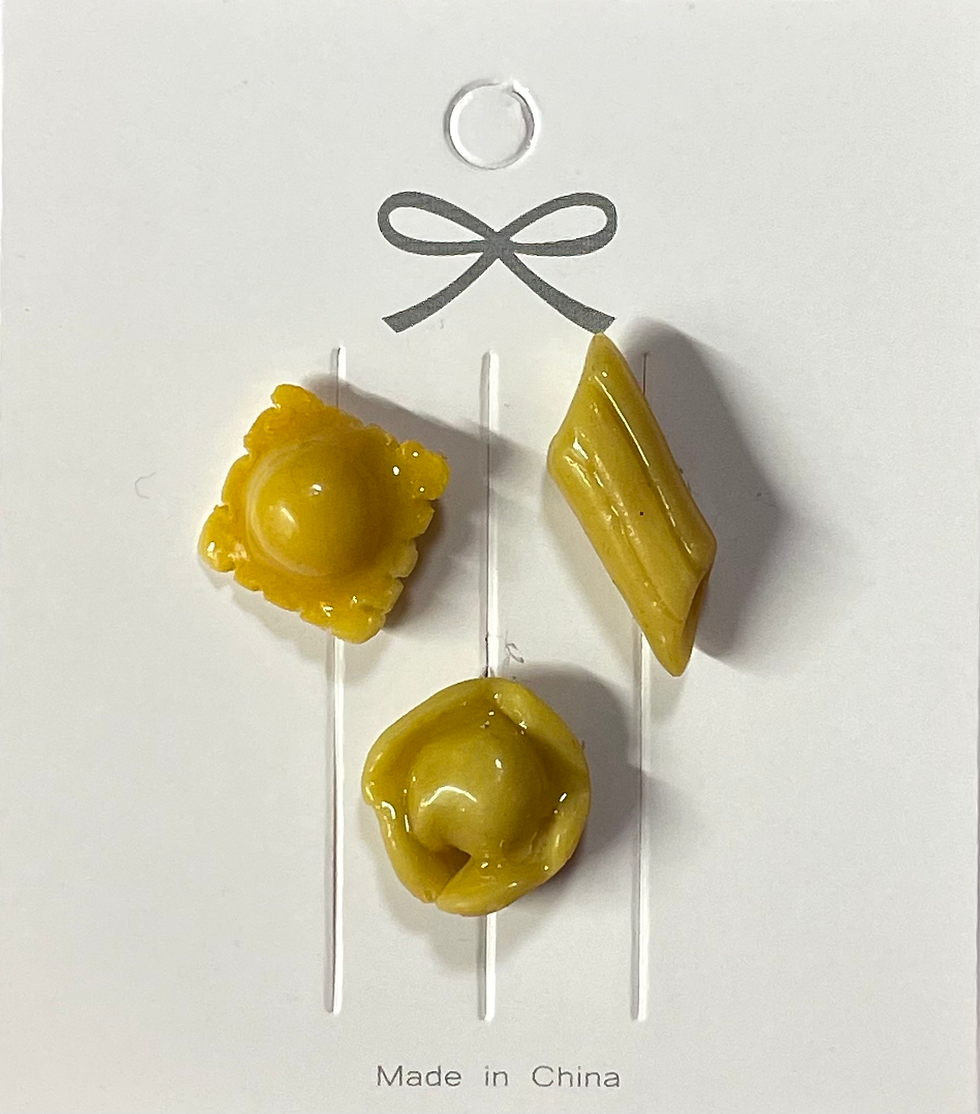 lapel pins of 3 types of pasta including a tortellini pin, a ravioli pin and a penne pin
