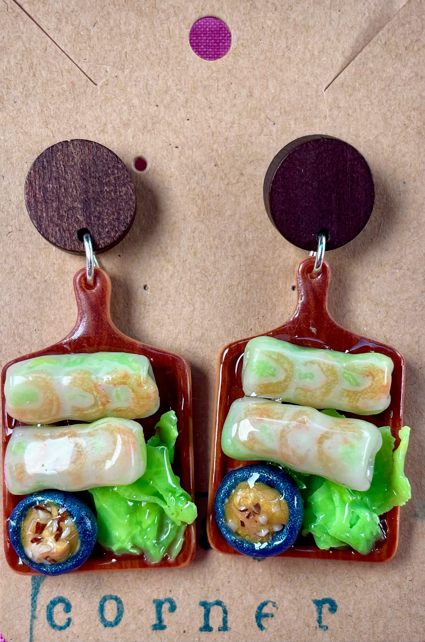 Earrings of shrimp spring rolls  and peanut sauce dip with nuts in a blue dipping bowl on a wood cutting board and lettuce