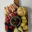 Thumbnail: magnet of wooden cutting board with bowl of olives raspberries brie cheese sour dough bread rolled ham and salami
