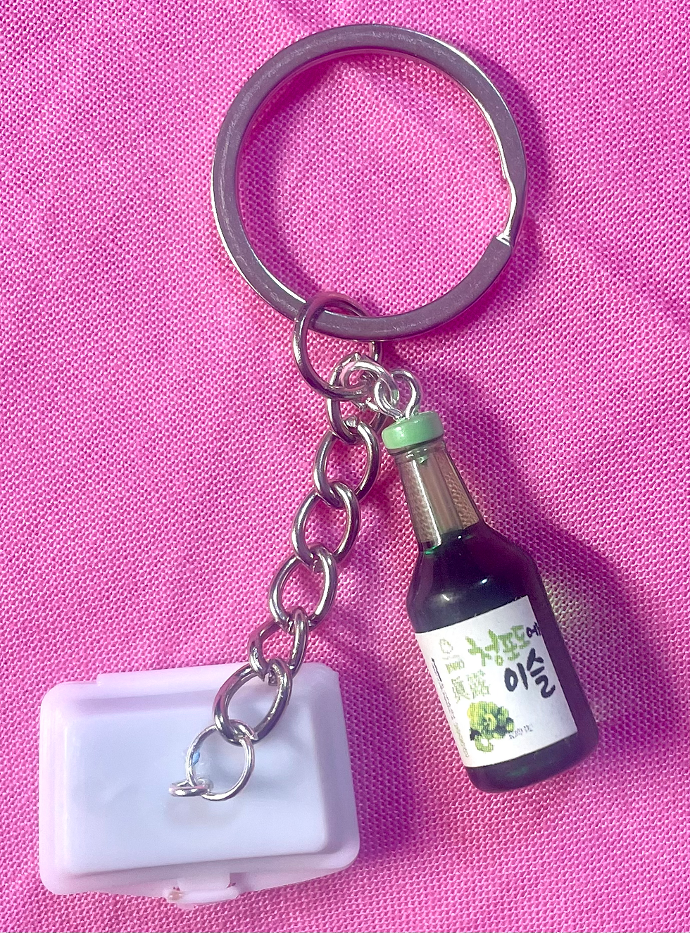 keychain of Japanese braised pork belly with scallions in a white takeout container and a sake bottle