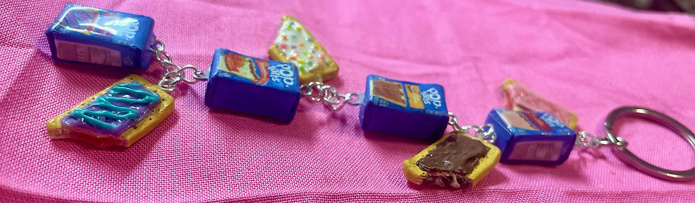 Thumbnail: keychain of 4 pop tarts including blue wild berry, cherry, strawberry and smores poptart, all pop tarts have a bite mark