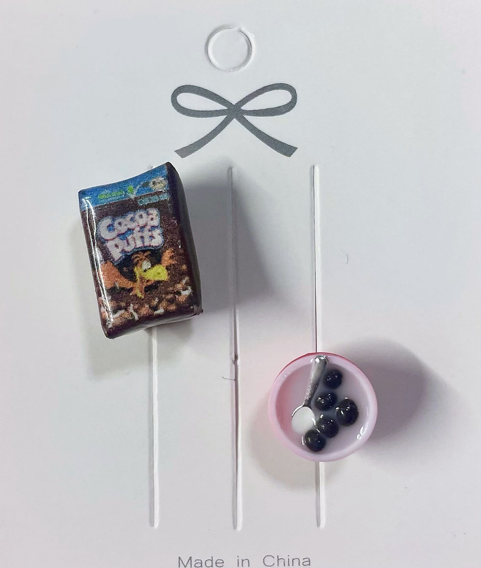 lapel brooch and pin of a cocoa puffs cereal box and a bowl of cereal with a tiny spoon in it