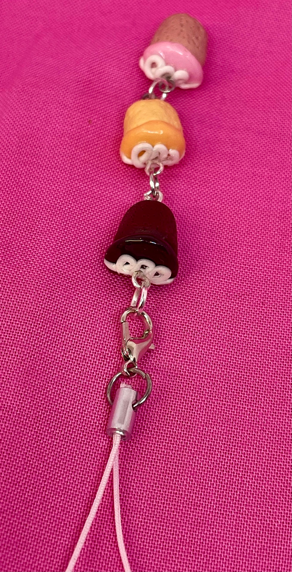 Thumbnail: phone charm of a chocolate hostess cupcake an orange hostess cupcake and a strawberry hostess cupcake