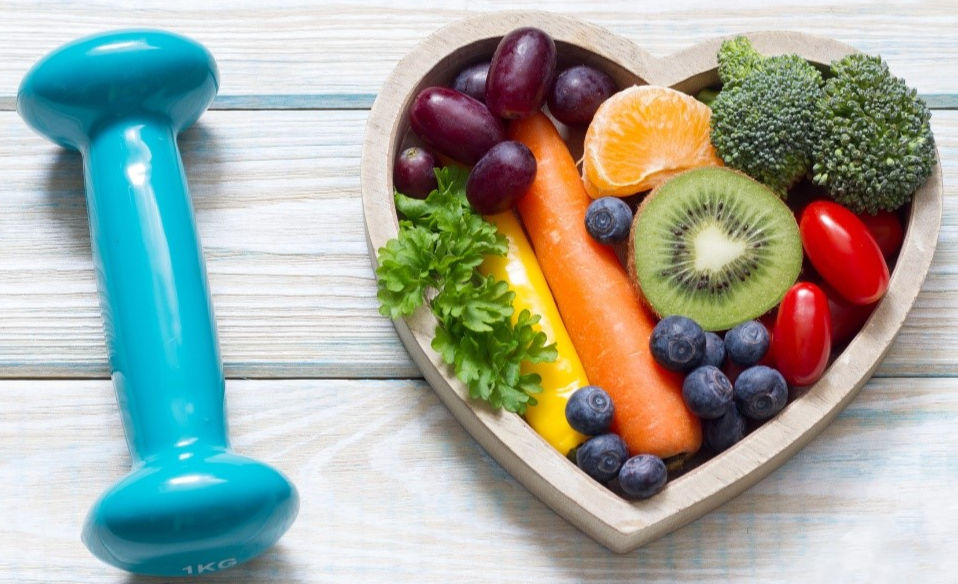 A dumbbell and a plate of fruits and vegetables