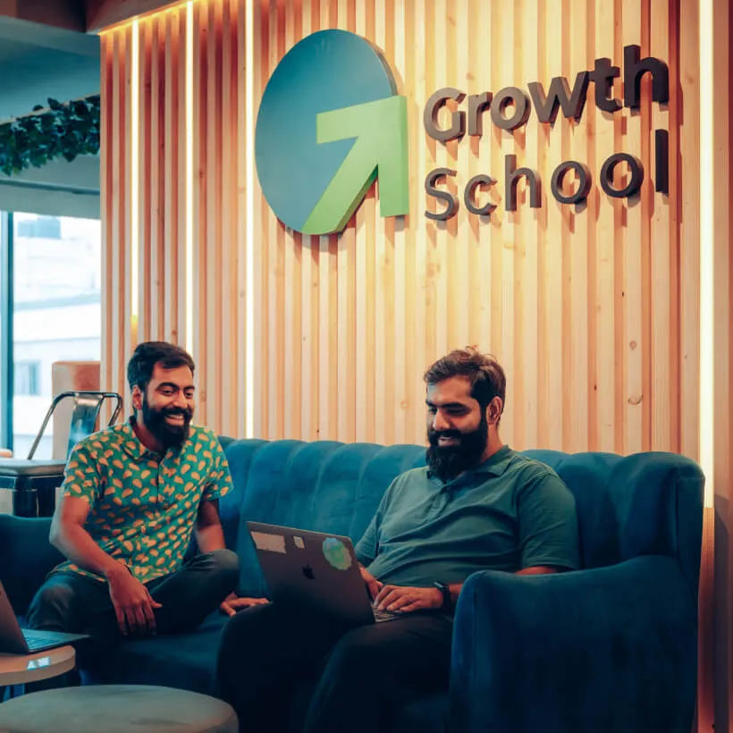 Two people working with a laptop in the GrowthSchool office lounge.