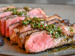 Sliced medium-rare steak topped with chimichurri sauce, highlighting upscale plating and bold food photography for NYC hospitality marketing.