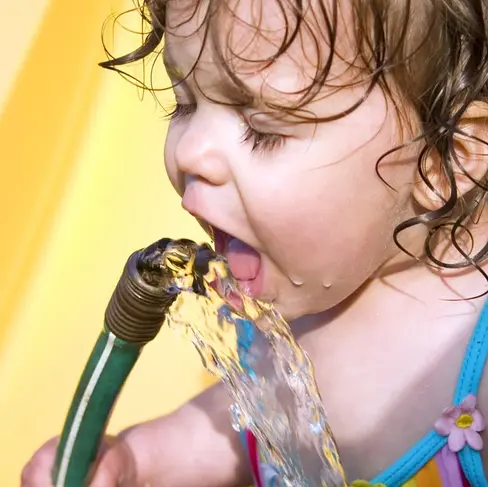 kid drinking from hose in summer