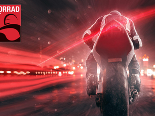Motorcyclist in black suit speeds through a city at night with red light trails. "MOTORRAD WELT BODENSEE" logo in the corner. Dynamic and intense mood.
