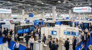 Crowded tech expo with attendees networking amid booths. Blue and white colors dominate. "Embedded World" signs visible above.