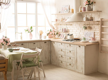 Cucina Shabby Chic con mobili bianchi e dettagli rustici, decorata con elementi vintage e piante.