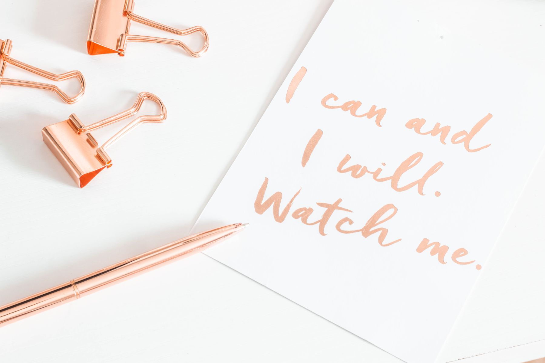 white desk with Positive affirmation written on paper in pink pen