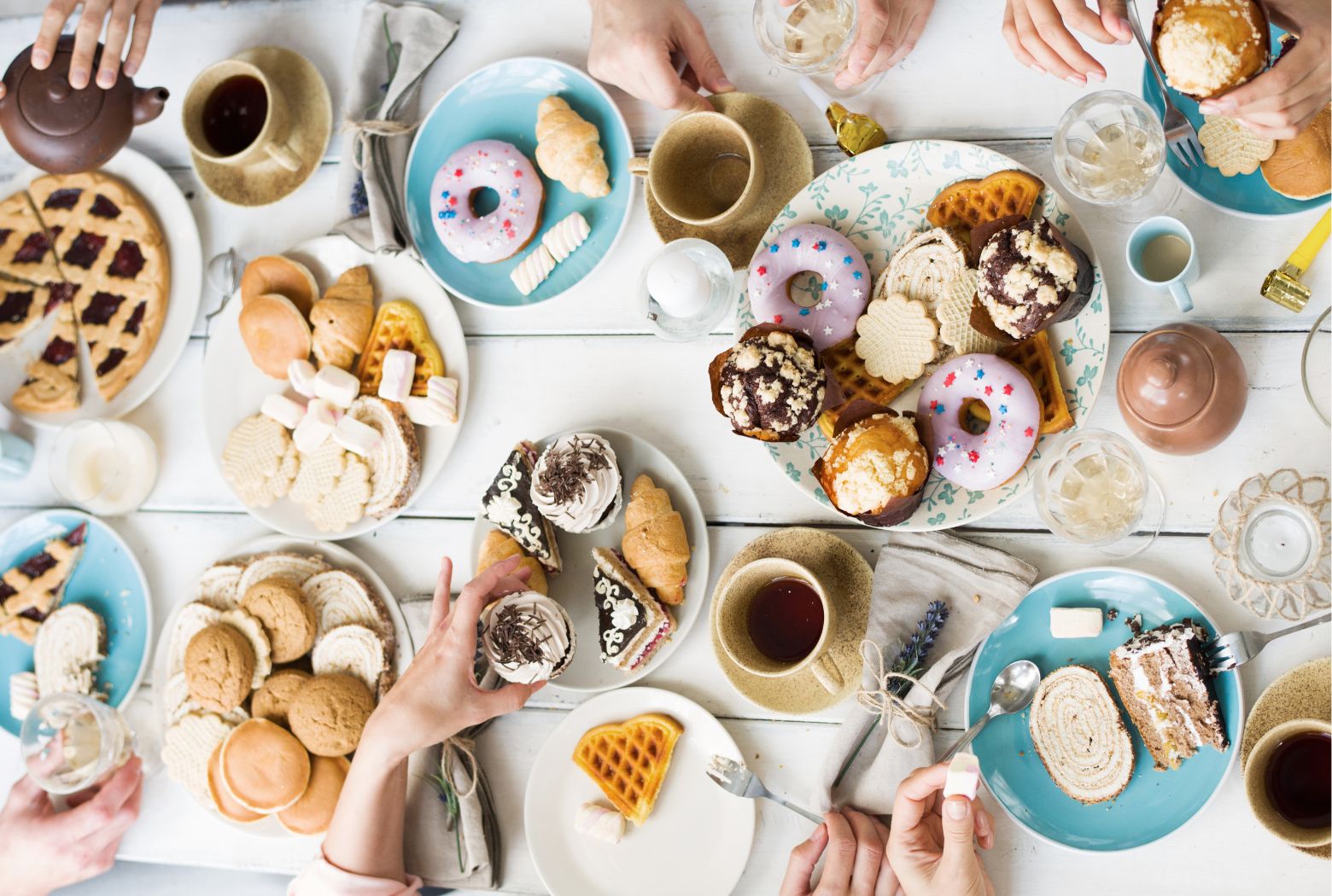 beautiful desserts including Cakes, cupcakes, brownies, coffee, tea on dinning table women's hands grabbing the food and emotionally eating 