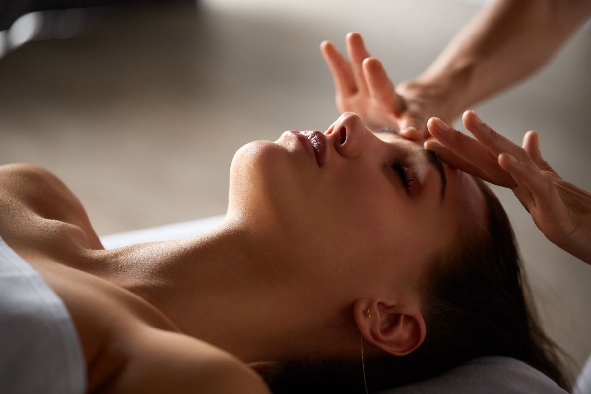 Spa therapist performing a face massage using Ayurvedic oil during a facial session.