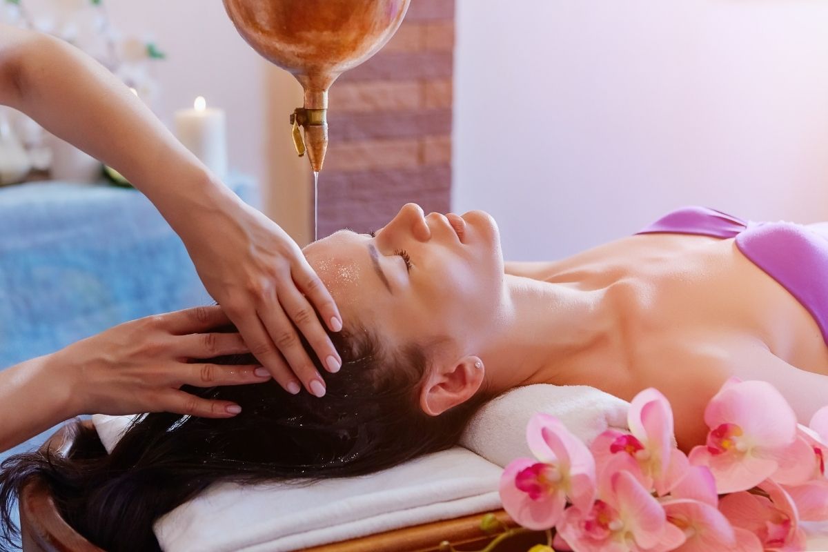 A therapist performing Shirodhara treatment by pouring warm oil over the forehead to induce relaxation and calm the mind.