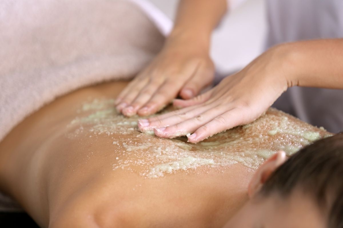An Ayurvedic therapist performing Udwarthnam massage using herbal powders to exfoliate and rejuvenate the skin.