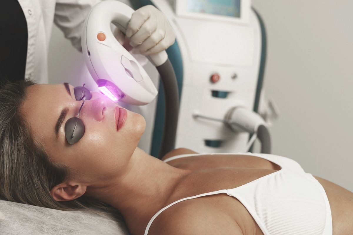 An IPL device emitting light pulses during a facial treatment to target skin concerns such as pigmentation and fine lines.