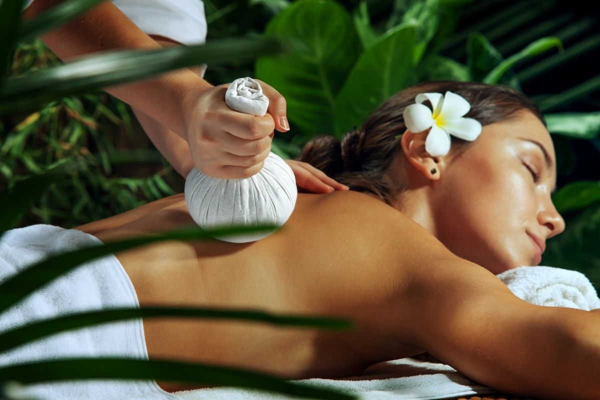 An Ayurvedic therapist performing Potli Therapy using herbal bundles to provide relaxation and healing.