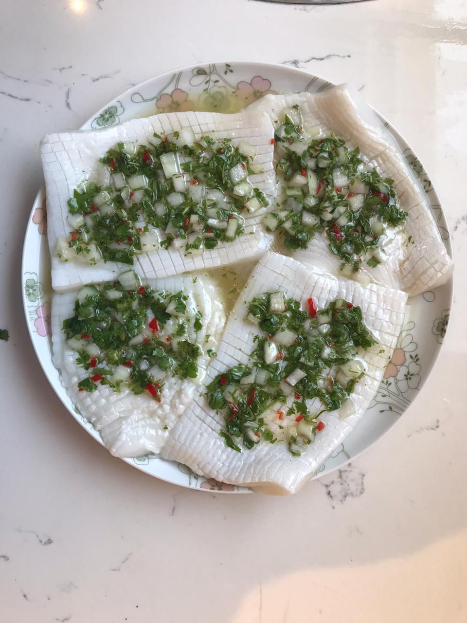Calamari steaks soaking in marinade. Coriander, chilli and lime. Food prep photo