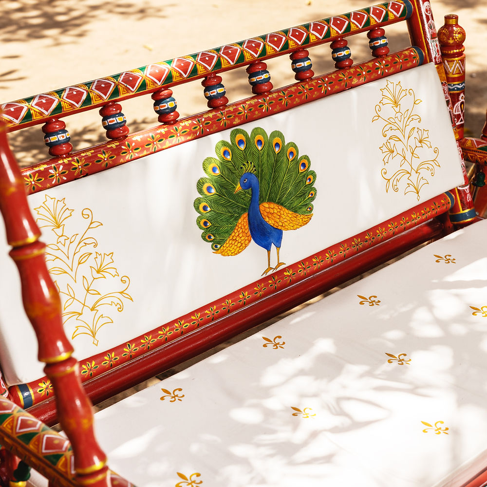 Red wooden swing with peacock painting and gold floral patterns