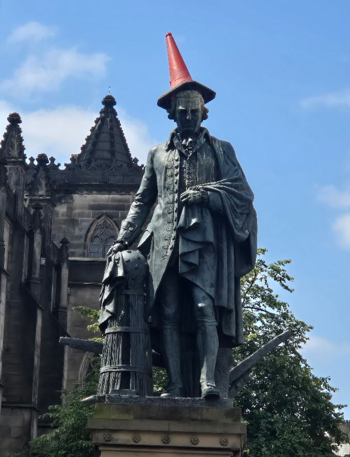 Adam Smith with a traffic cone on his head -- they really do crown statues with traffic cones