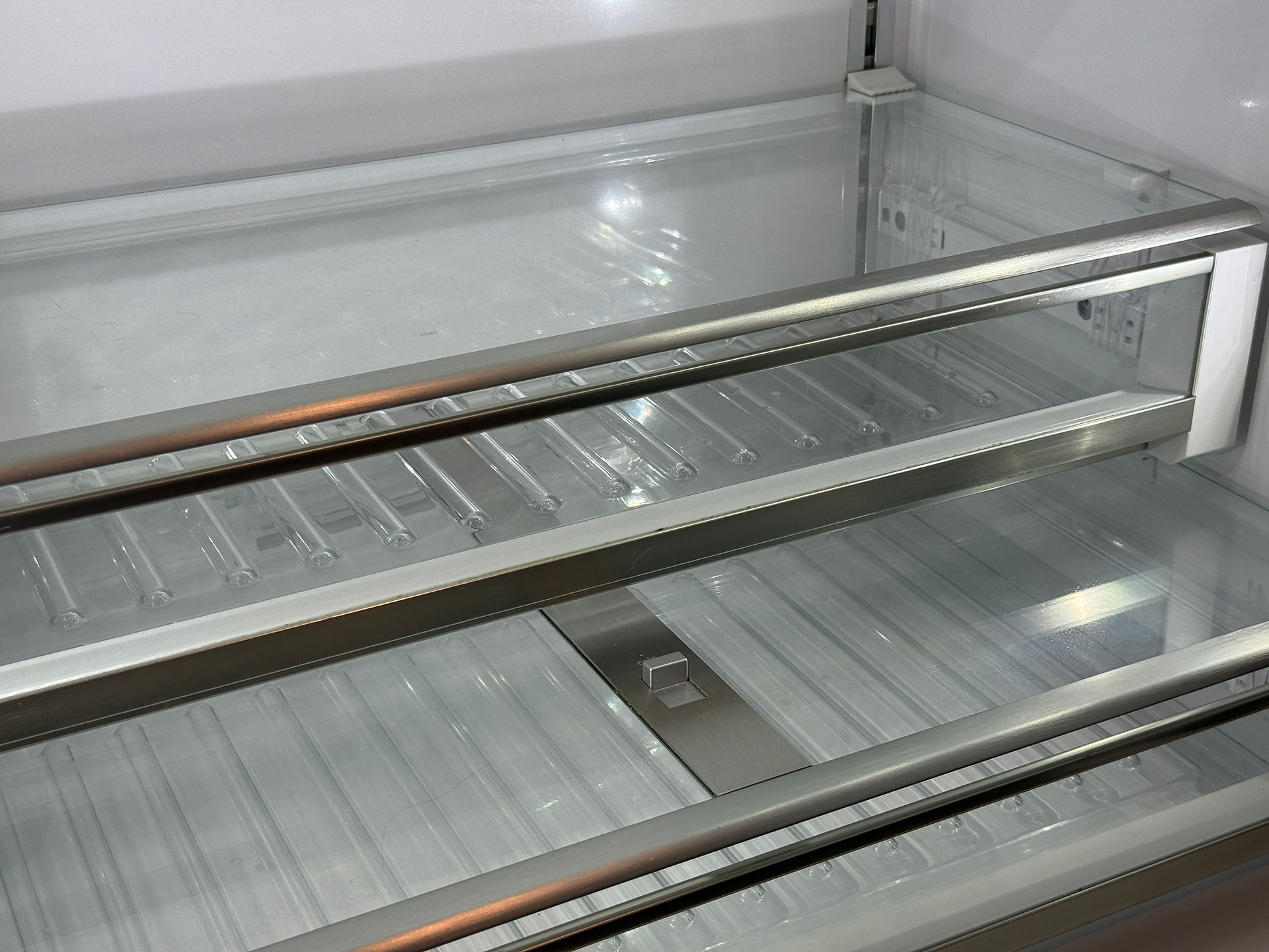 Spotless, transparent glass refrigerator shelves after a professional deep clean.