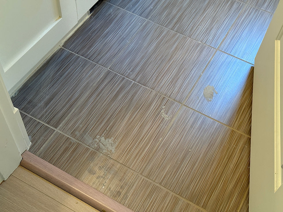 Dark tile flooring covered in white dusty footprints and construction residue in a Surrey home.