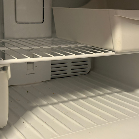 Refrigerator shelves with food crumbs prior to a move-out clean.