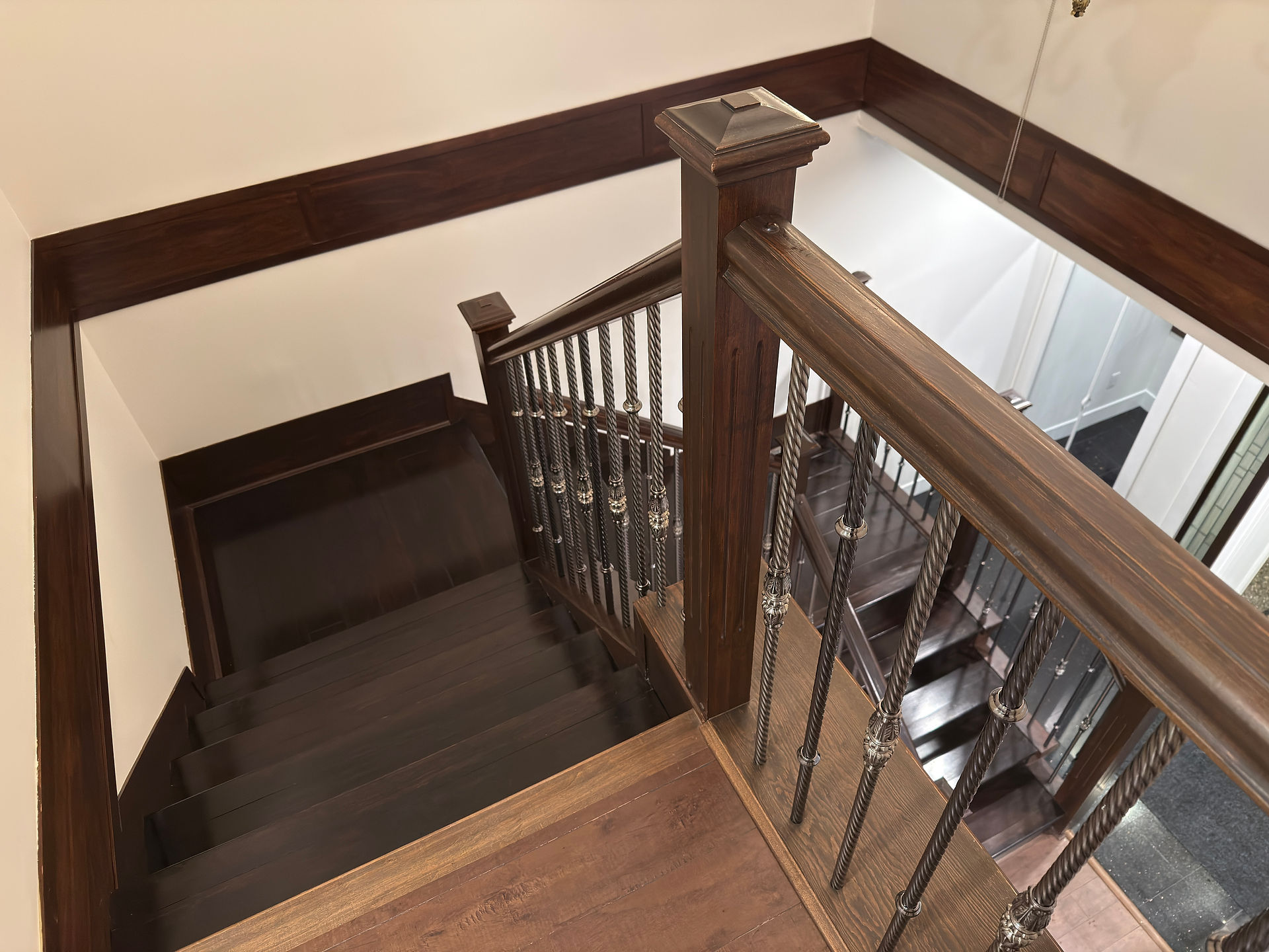 After photo of house staircase with dust removed from dark wood treads and railings during post-renovation cleaning.
