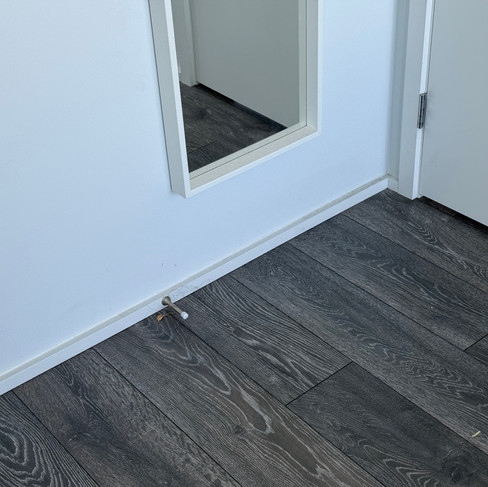 Dusty floor near a mirror and door.