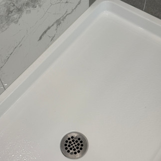 Professionally cleaned white shower base in Langley showing spotless drain area after move-out cleaning by OnePro Cleaning.