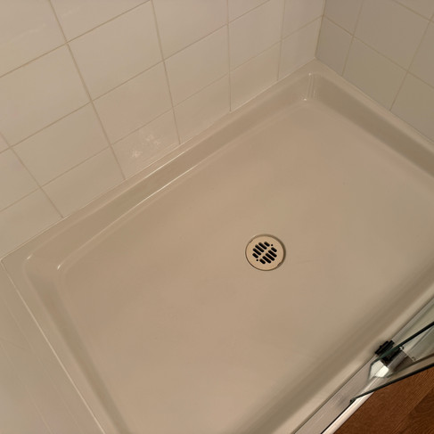 Spotless white shower pan after professional post-renovation cleaning in Coquitlam.