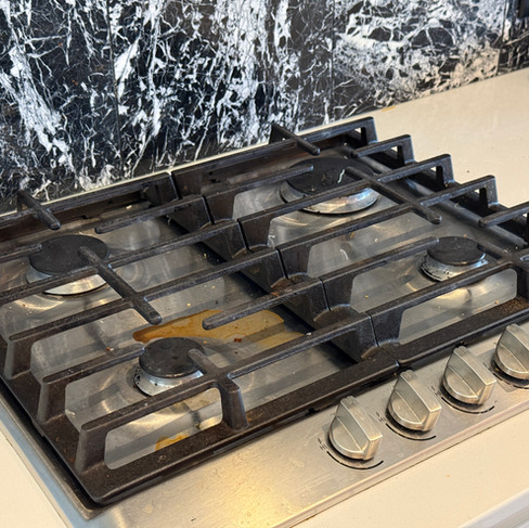 Dirty gas stovetop covered in grease and food spills before a move-in clean.