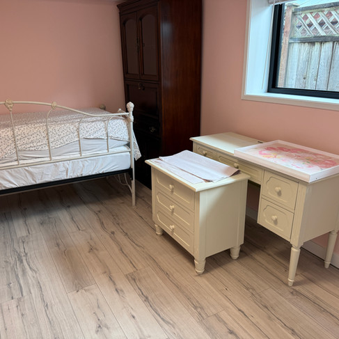 Clean pink bedroom with an uncovered white bed frame and dust-free hardwood floors after renovation detailing