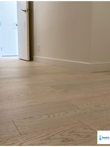 Clean engineered hardwood floors and dusted baseboards in an empty apartment ready for handover