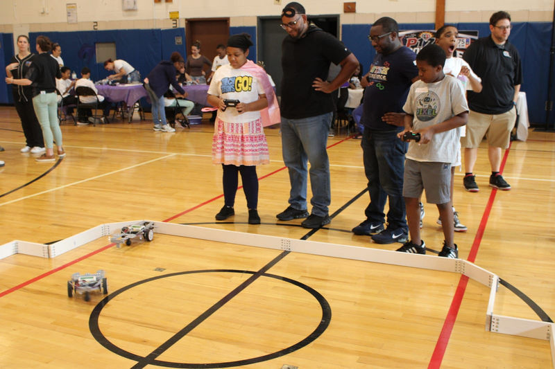 Students drive their robots around the arena during a match.