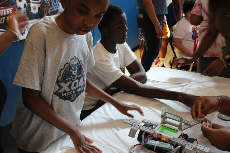 Students build and wire their robots at a table before the competition.