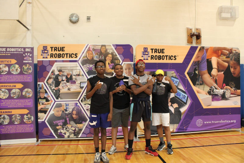 A student team poses at the True Robotics backdrop.