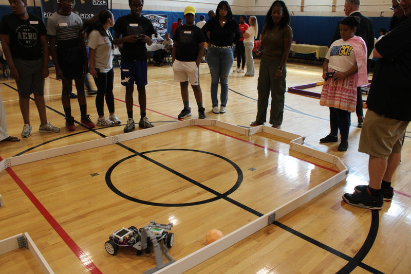 Teams and families gather around the arena as robots compete on the gym floor.