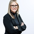 Professional corporate headshot of businesswoman in black blazer on neutral grey background, photographed in Prescott Ontario