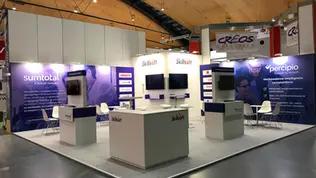 Изложбен щанд на Skillsoft на изложение в Карлсруе, представящ платформи за дигитално обучение SumTotal и Percipio. Щандът е с отворена структура, с няколко обособени зони за разговори, брандирани рецепции и стени с информационна графика. Включени са четири екрана, монтирани на вертикални панели и стени, използвани за видео съдържание и демонстрации. Дизайнът е изчистен и подчертано корпоративен, с доминиращи цветове бяло, лилаво и сиво. Щандът комуникира модерни HR и e-learning решения за корпоративния сектор.
