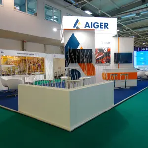 Изложбен щанд на компанията AIGER на WT Europe. Щандът е с модерна визия в бяло, синьо и оранжево, с две зони за срещи, всяка обзаведена с бели кожени кресла и бар маси с високи столове. В горната част има светеща конструкция с логото на AIGER. Декоративни бели пръчки разделят пространството. На стените са монтирани няколко екрана. Подът е покрит със син мокет.