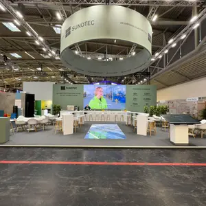 Просторен изложбен щанд на Sunotec на изложението Intersolar, с висящ овален банер с брандиране, голям LED екран в центъра на стената и LED екран, вграден в пода. Щандът разполага с отворени зони за разговори, високи и ниски маси, модерни бели столове и тъч скрийн за представяне на интерактивна карта. Дизайнът съчетава функционалност, технологии и изчистена визия, подходяща за международно B2B представяне.
