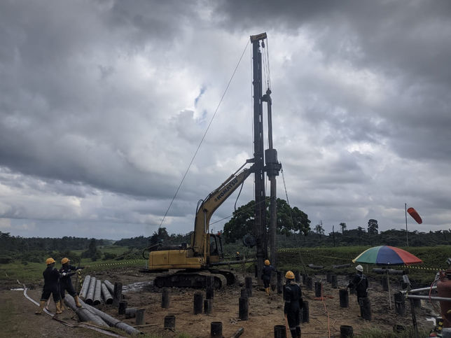 Construction team collaborating to install a vertical pipe at the Walio Papua oil storage site