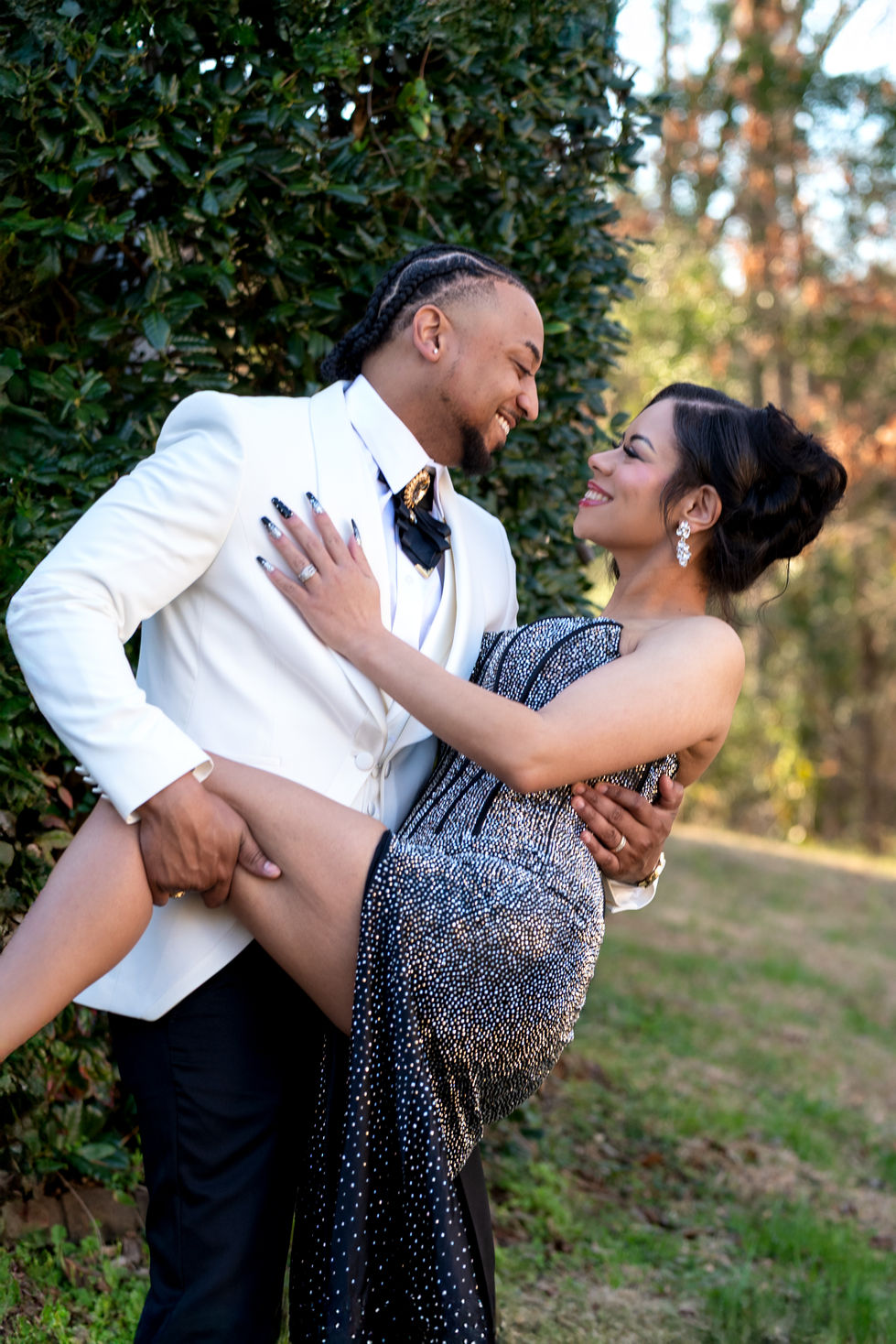 Couple posing elegantly outdoors in formal attire.