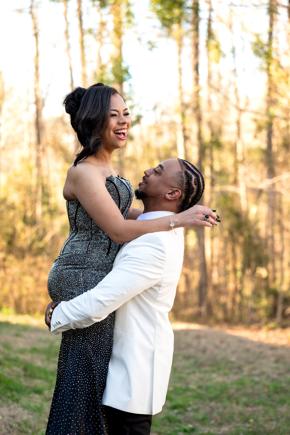 Couple embracing outdoors, smiling in formal attire.