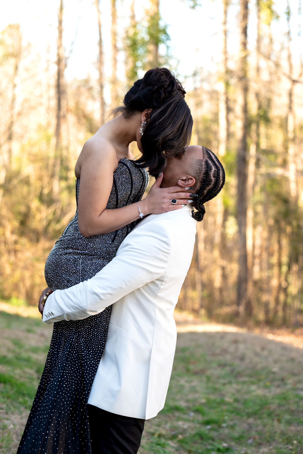 Couple embracing outdoors, man lifting woman.