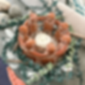 Close-up of decor featuring a candle holder of terra cotta circle of humans with their arms around each other and a spray of eucalyptus branches around the outside