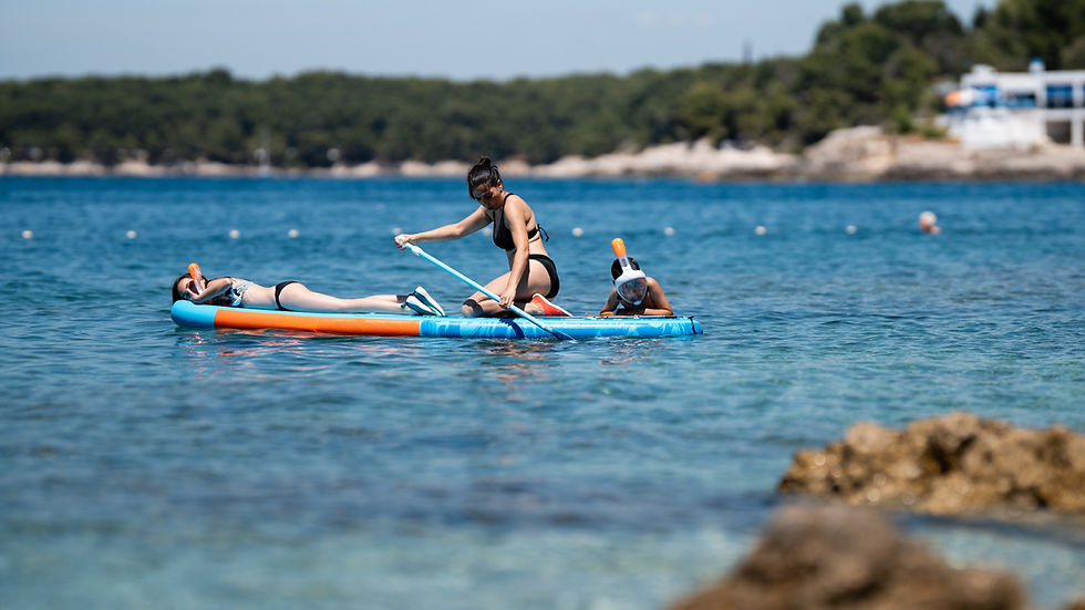 Mother paddling with kinds while they snorkle.